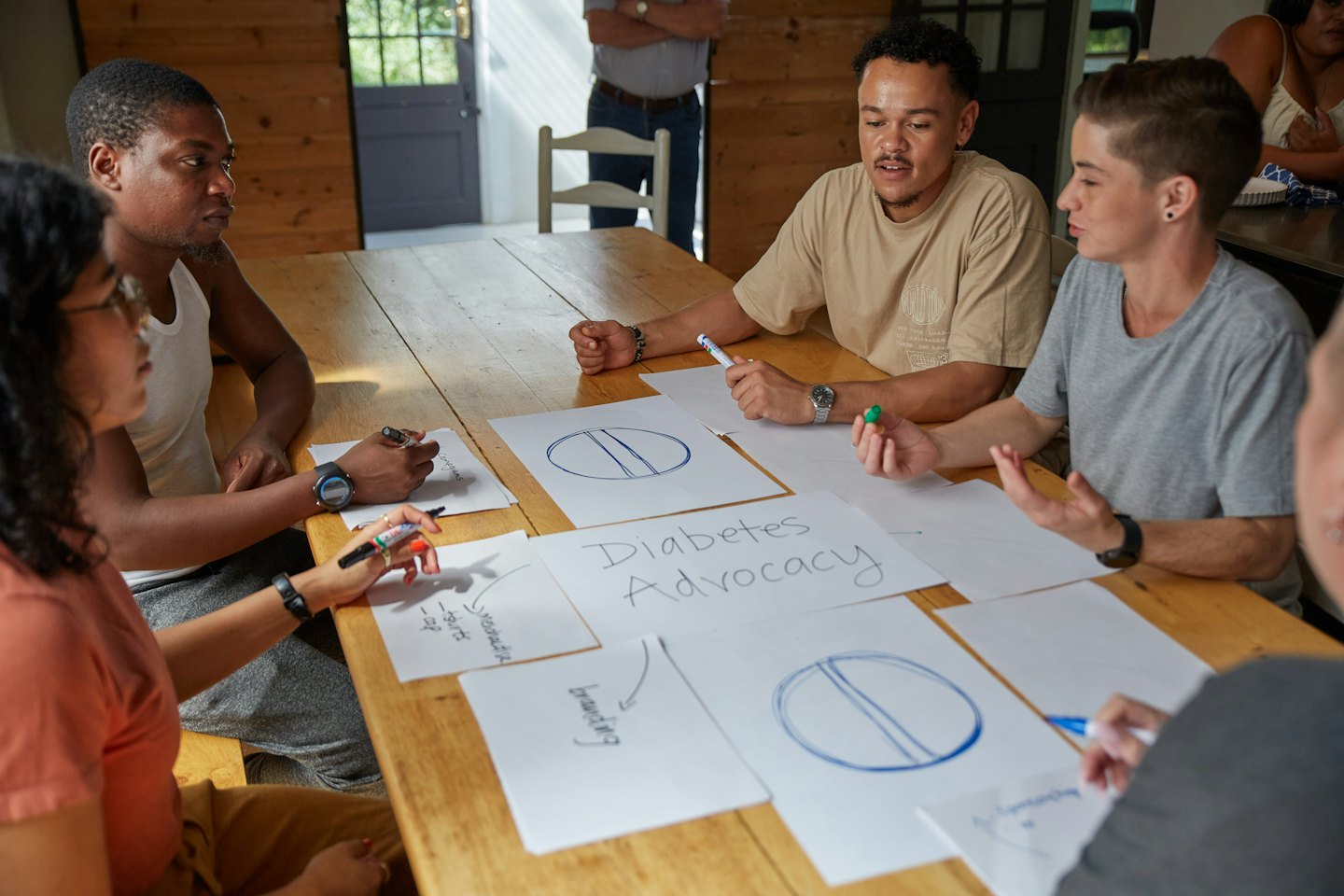 Diverse young adults collaborate on diabetes advocacy ideas at a table.